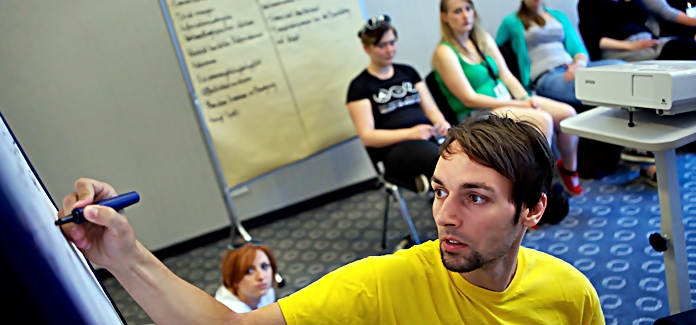 Junger Mann schreibt an ein Flipchart