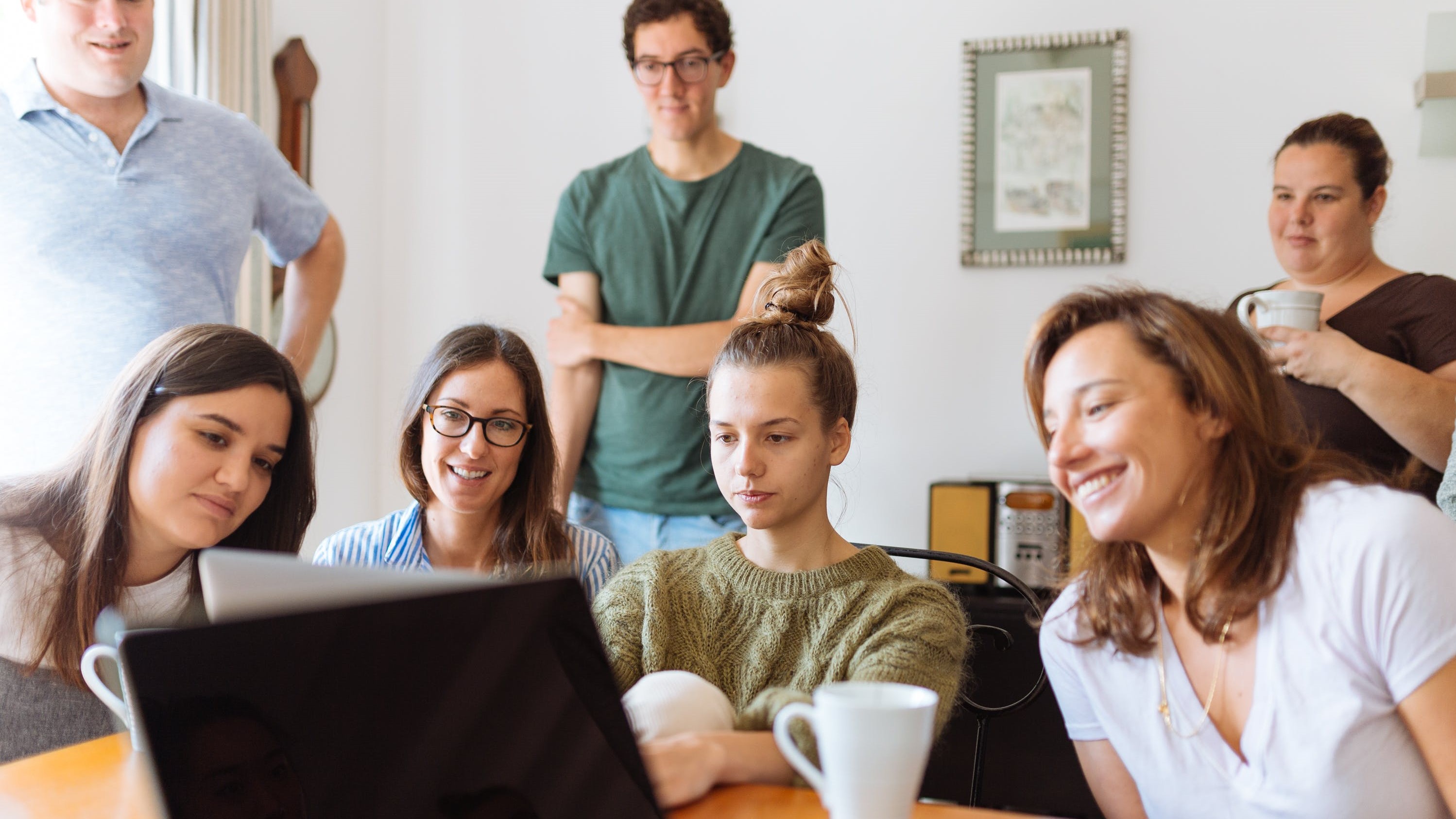 Gruppe Lernender um einen Laptop