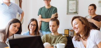 Gruppe Lernender um einen Laptop