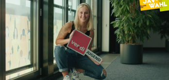 junge Frau in Hocke mit ver.di Jugend Schild in der Hand